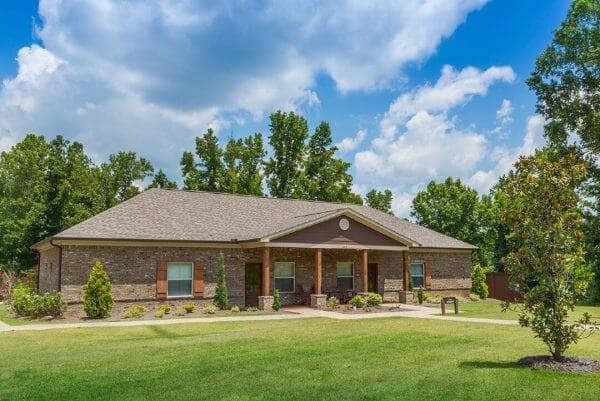 log cabin building with grassy front yard and tall trees