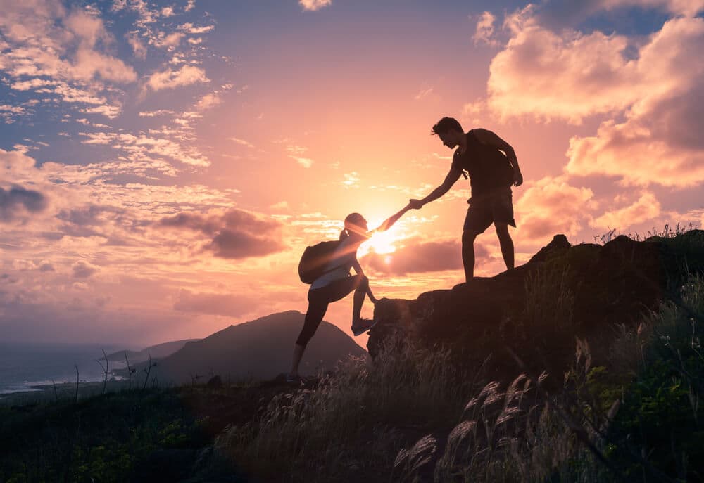 man helping climber up a mountain