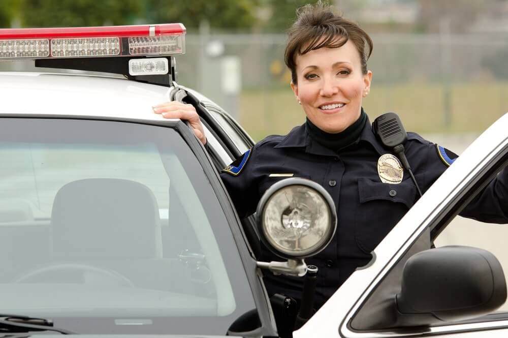 female police officer standing by squad car with door open