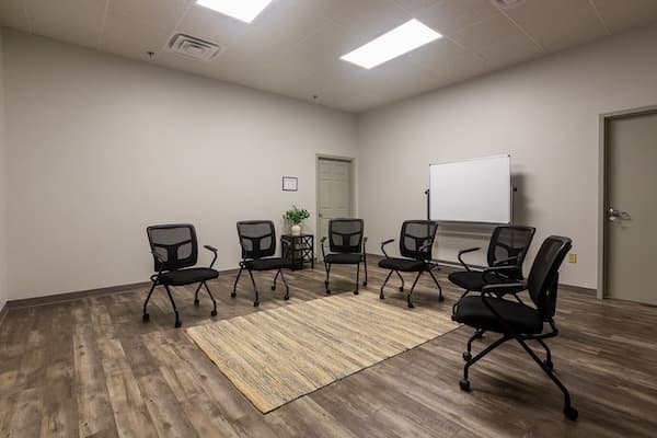 Clean room with chairs around a rug and wood floors