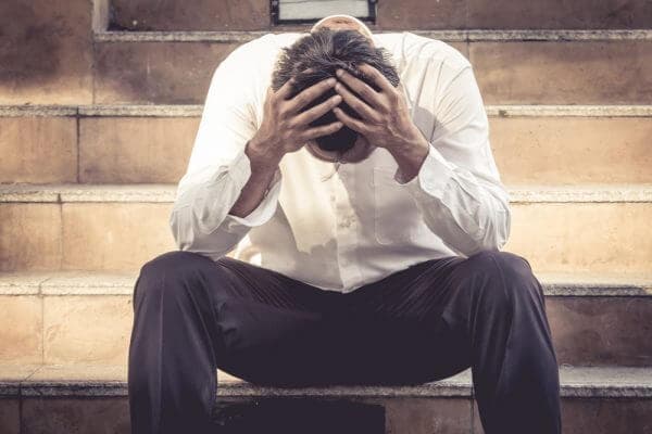 man sitting on steps with head in his hands